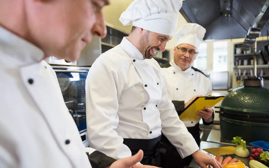 Professional chefs preparing fresh vegetables while a supervisor checks kitchen operations.