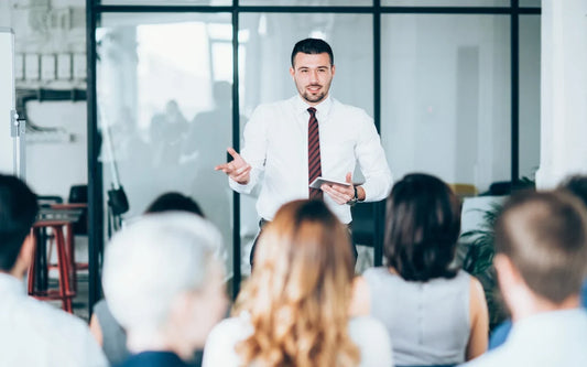 Training graphic for the course "AI Learning Analytics for Corporate Training Guide" showing a business presenter addressing a seminar audience.