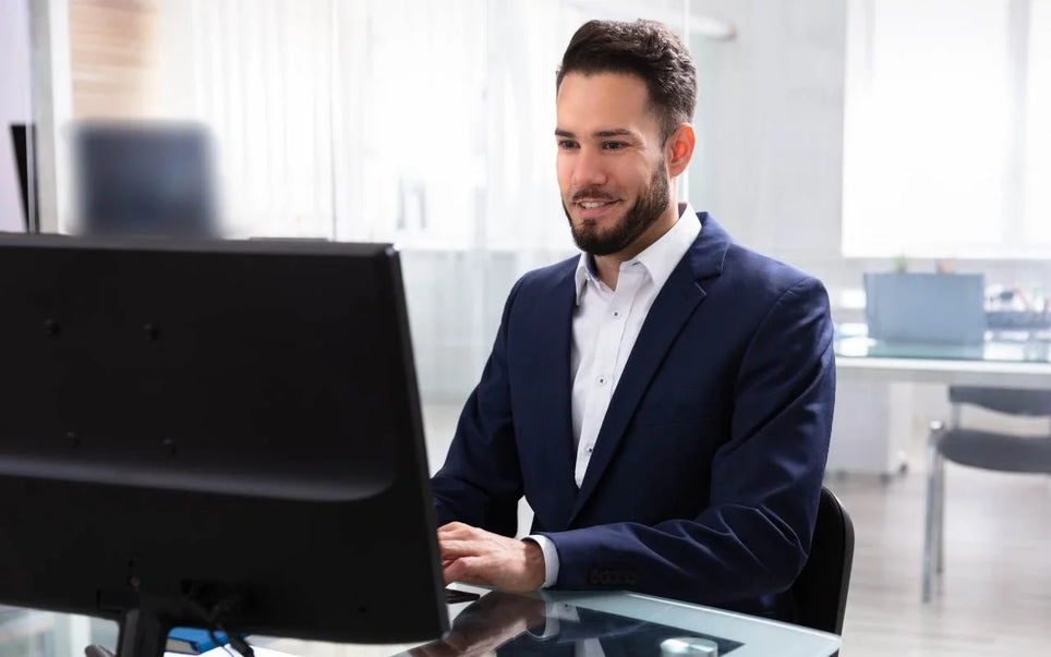 A professional man in a suit working on a computer in a modern office environment for EU AI Act Certification training