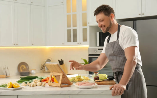 Food handler completing online food safety training in a home kitchen in Spain, preparing ingredients while following 2026 food hygiene regulations and certification requirements.