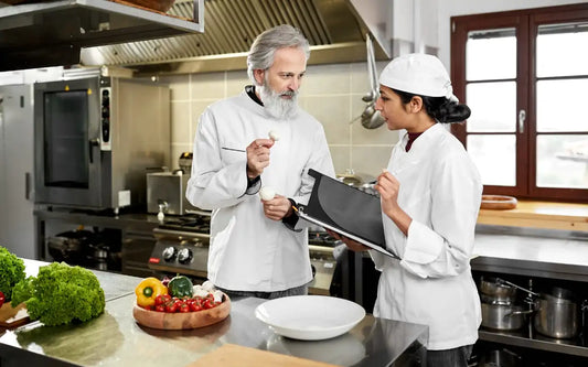 Food hygiene trainer guiding a kitchen worker on food safety practices and hygiene standards as part of Food Hygiene Certificate training in Spain for 2026 compliance.