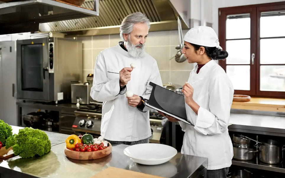 Food hygiene trainer guiding a kitchen worker on food safety practices and hygiene standards as part of Food Hygiene Certificate training in Spain for 2026 compliance.