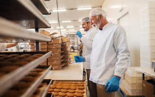 HACCP Training for Food Handlers in Spain featuring food production workers following hygiene and food safety procedures while inspecting baked goods in a commercial food processing facility.