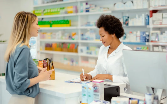 Age limits to buy paracetamol guide banner showing a customer talking to a pharmacist at a pharmacy counter