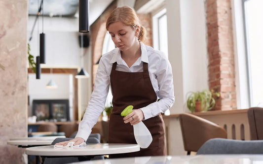 Jobs for Teenagers in Spain guide banner showing a young waitress cleaning a cafe table with a spray bottle