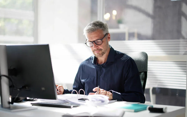 Minimum Wage Spain 2026 guide banner showing an accountant reviewing payroll documents at an office desk