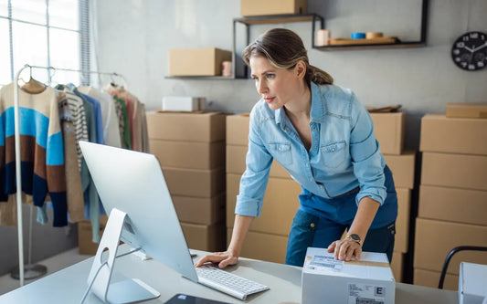 SME Cybersecurity and Digital Compliance in Spain banner showing a businesswoman using a computer in a shipping and fulfillment office