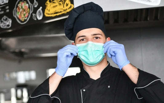 Educational guide banner for "Fitness to Work: Should Food Handlers Wear Gloves? Rules & Best Practice," depicting a commercial kitchen worker demonstrating proper personal protective equipment (PPE) and food hygiene compliance.