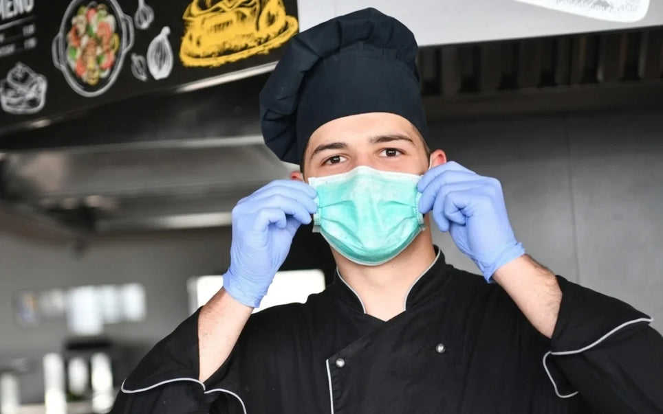 Educational guide banner for "Fitness to Work: Should Food Handlers Wear Gloves? Rules & Best Practice," depicting a commercial kitchen worker demonstrating proper personal protective equipment (PPE) and food hygiene compliance.