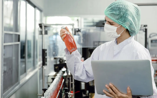 Food handler inspecting a bottled food product in a production facility while preparing for the Spain Food Handler Test, food safety quiz, and certification assessment.