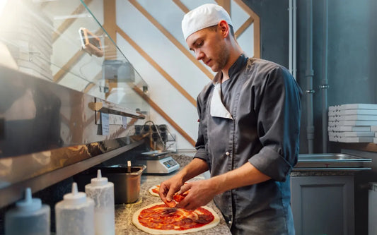 Street food worker preparing fresh pizza in Spain, demonstrating proper food handling practices, hygiene standards, and food safety compliance for street food vendors in 2026.