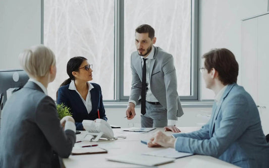 Business professionals in a formal office setting having a tense discussion around a table during a meeting