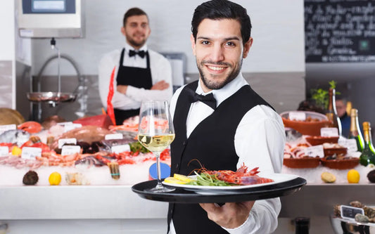 Professional waiter carrying a prepared seafood dish in a restaurant.